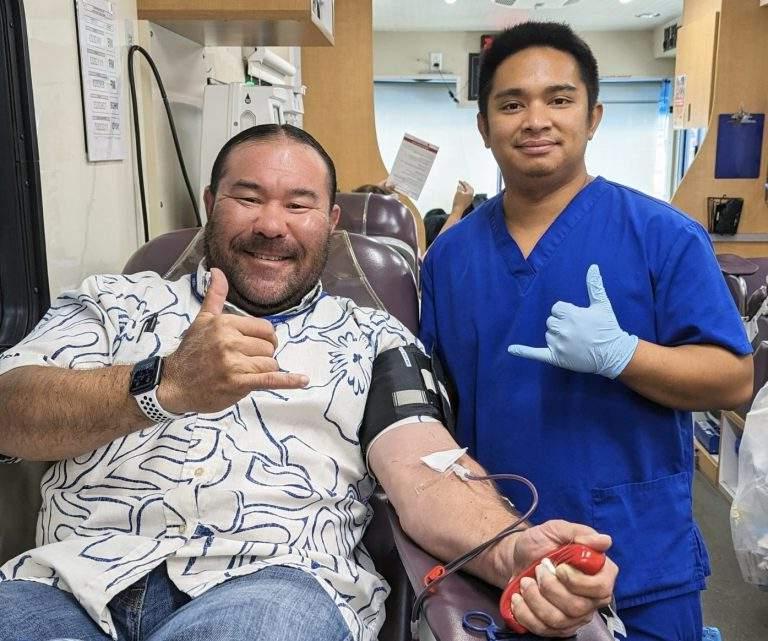 Blood bank staff and 澳博体育app下载 blood donor smile and give shakas during a donation.